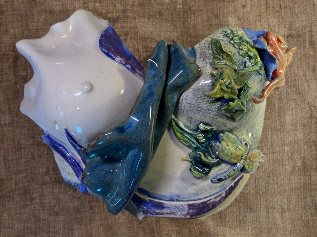 Ceramic sculpture with sculpted creatures climbing flowing forms